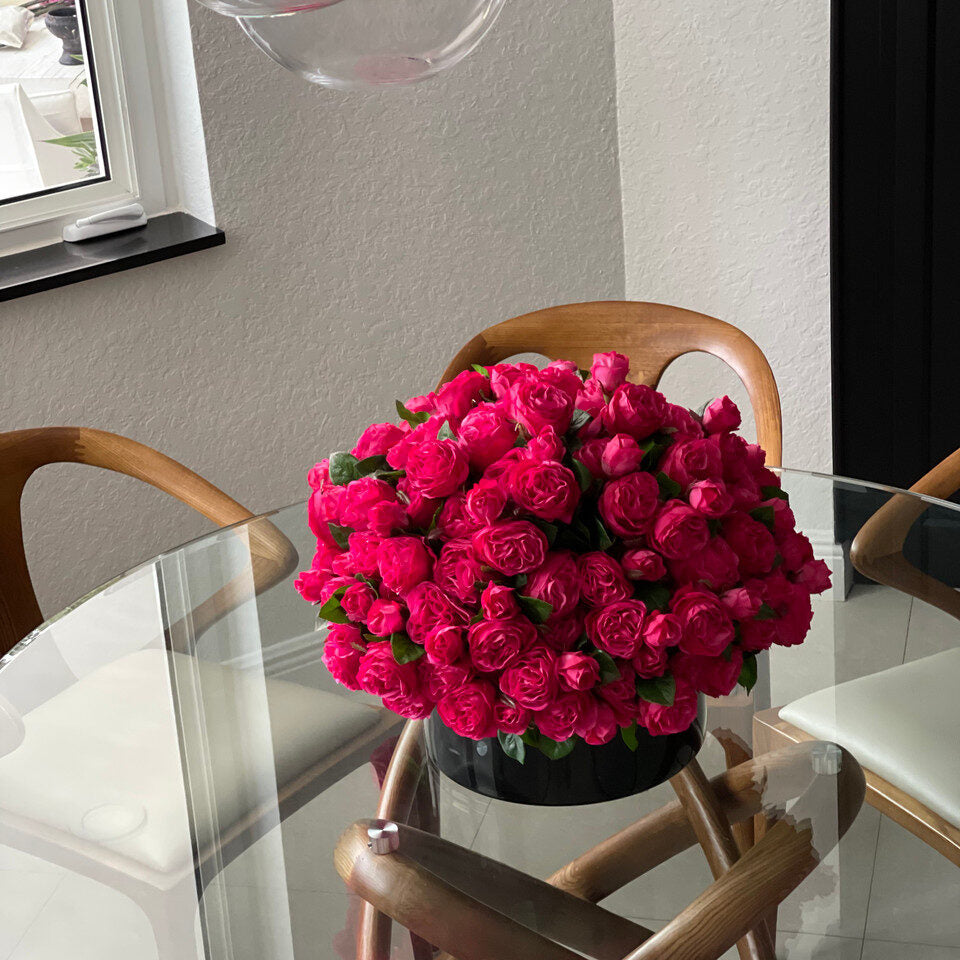 Roses anglaises rose foncé dans un vase en verre noir