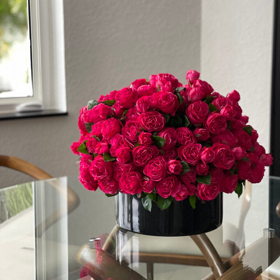 Roses anglaises rose foncé dans un vase en verre noir