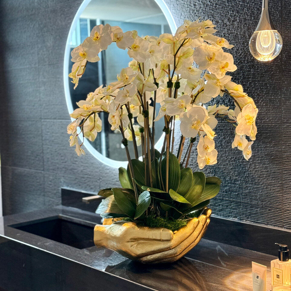 Orchidées Phalaenopsis blanches dans un vase sculpture doré en forme de mains ouvertes