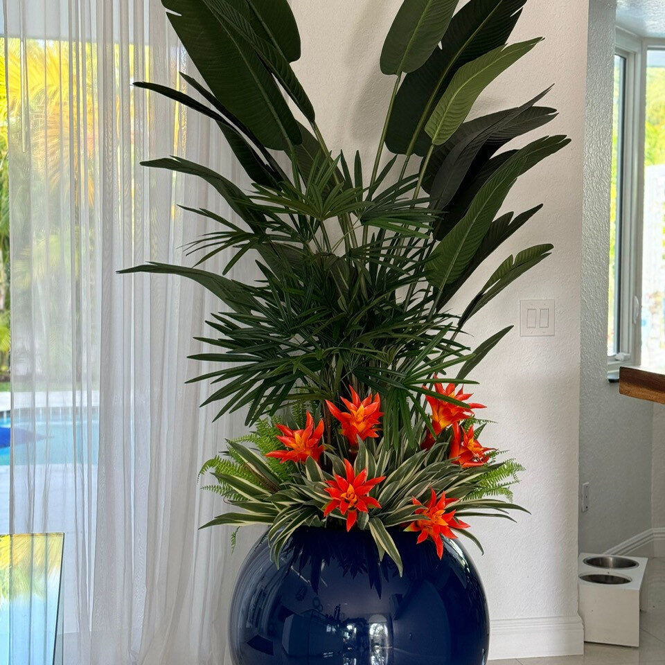 Plantes tropicales mélangées dans un pot globe bleu cobalt