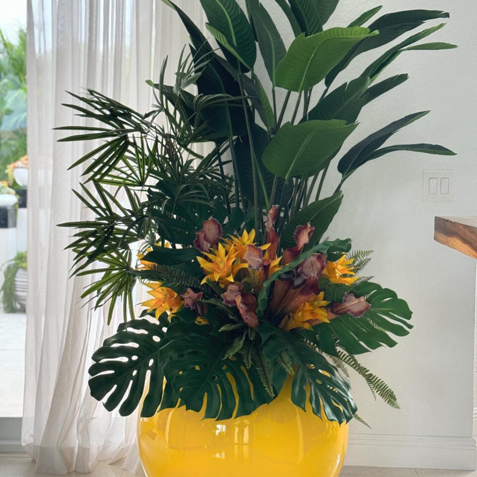 Mélange de plantes tropicales dans un pot globe jaune