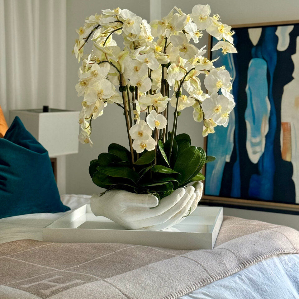 Orchidées Phalaenopsis blanches dans un vase sculpture en forme de mains ouvertes blanches