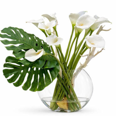 Vase lune soufflé à la main avec des arums et des feuilles de monstera