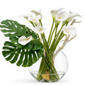 Vase lune soufflé à la main avec des arums et des feuilles de monstera